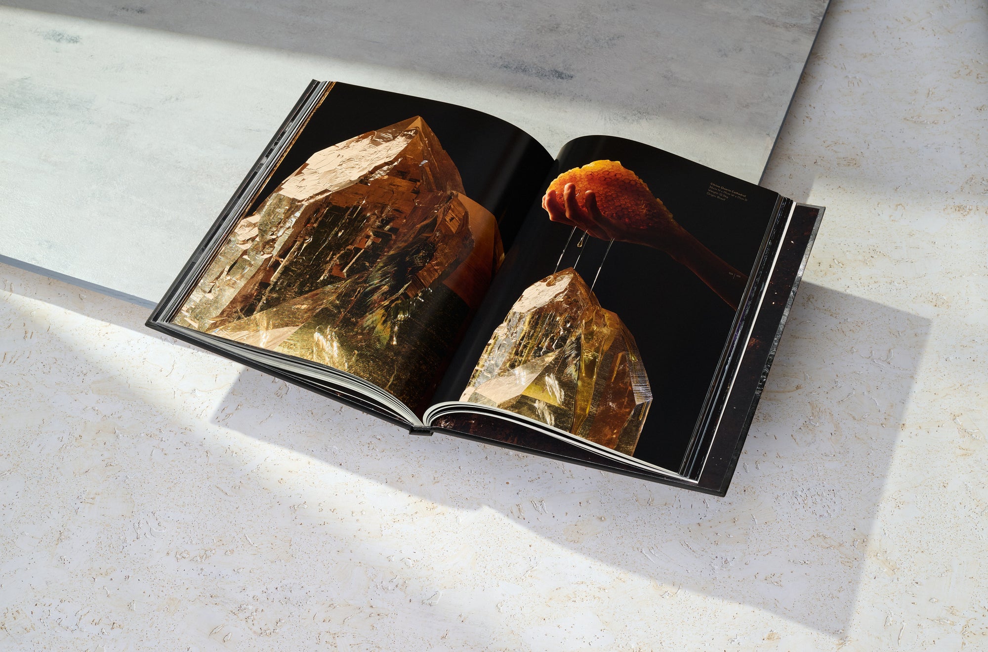 View of interior spread from the book ARQUIVISTAS by the Dorow Collection. Macro view of giant quartz and wider image of a hand holding a honey comb dripping honey on the top of the citrine quartz. 