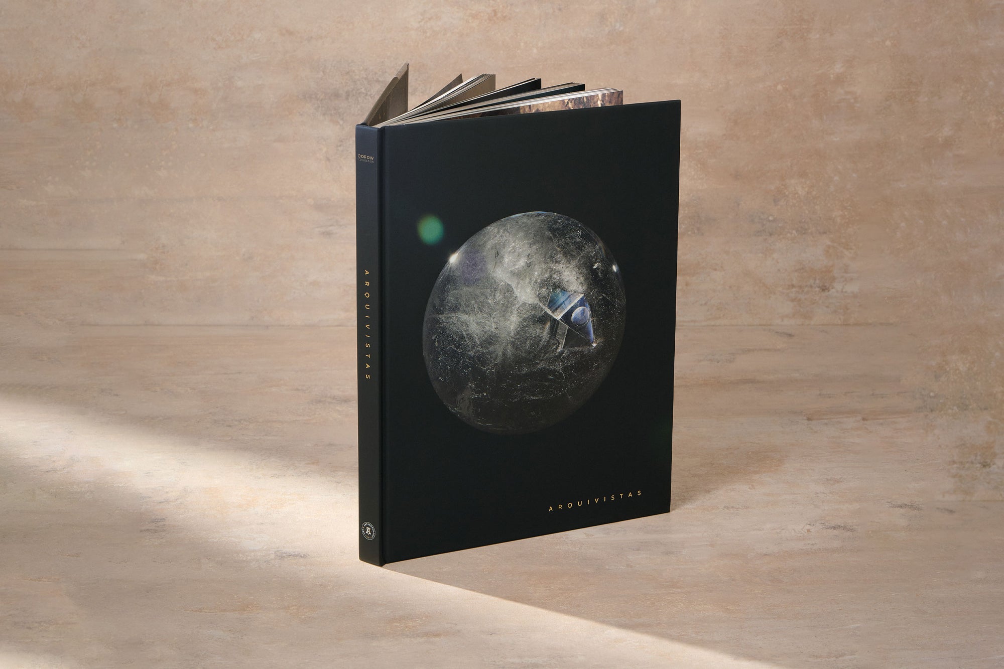 Cover Image of the book ARQUIVISTAS by the Dorow Collection. Cover shows an Enhydro Quartz Sphere suspended in the middle of deep black background. 